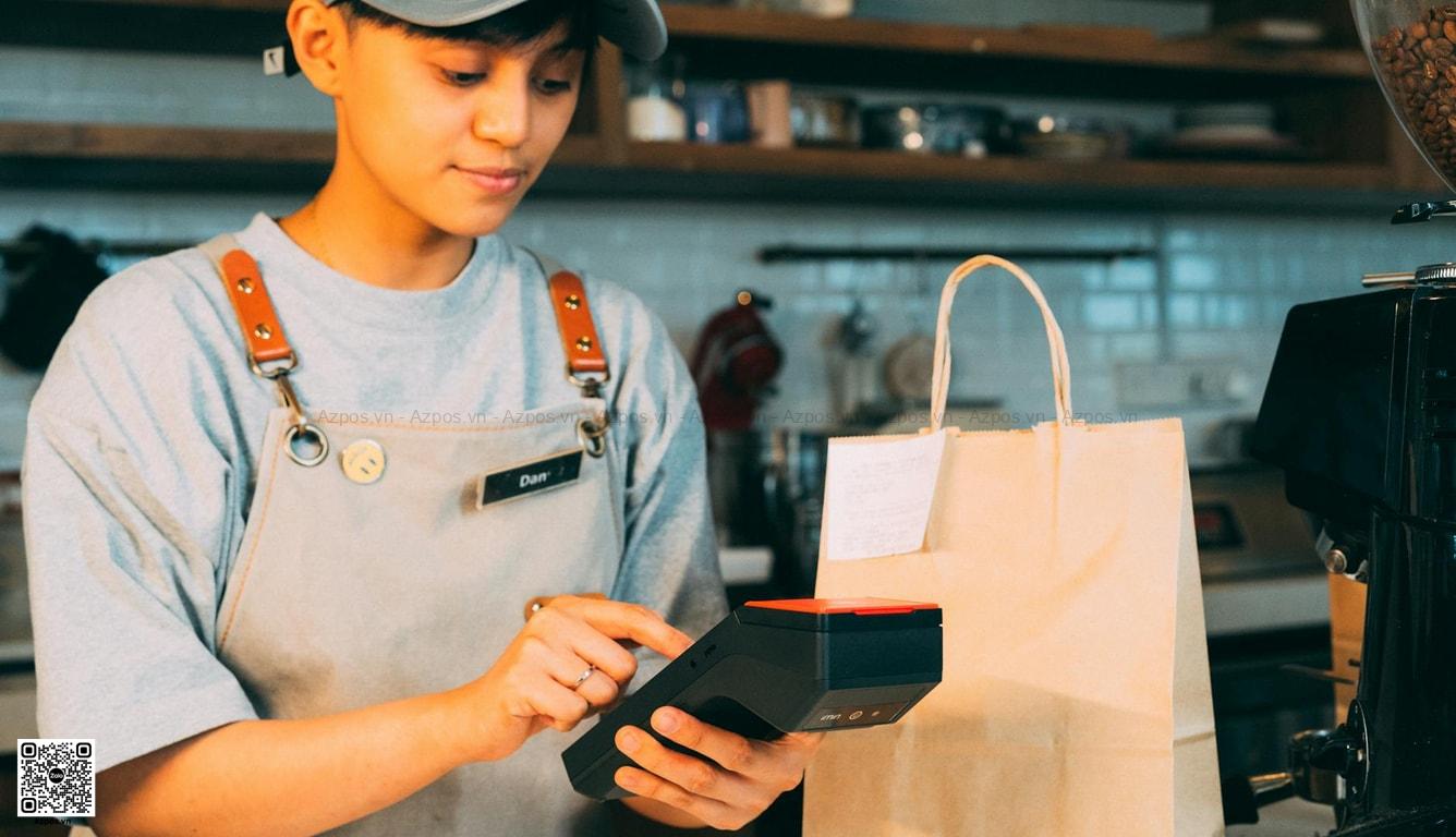 Nhân viên quán cafe thao tác máy POS tại quầy thu ngân