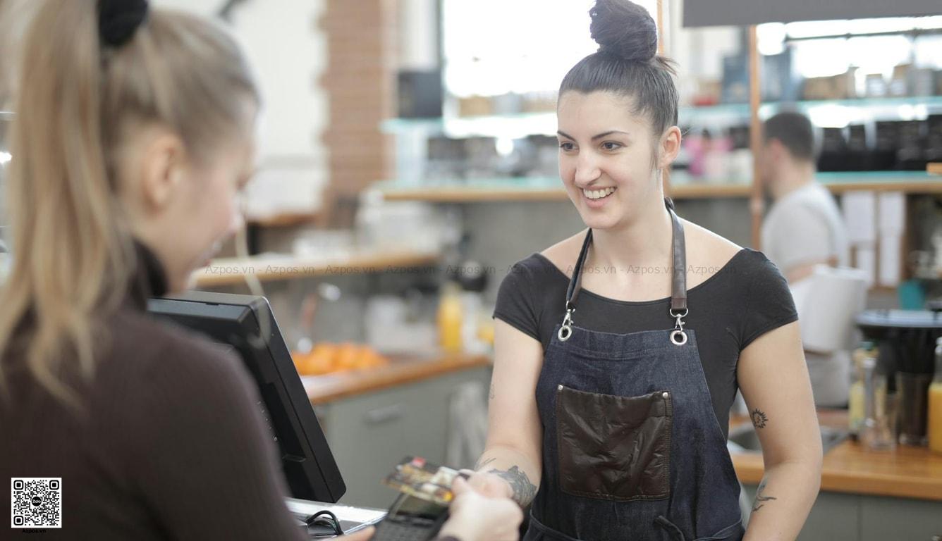 Khách thanh toán tại quầy cafe với máy in bill và POS