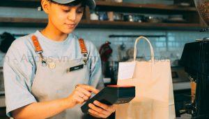 Nhân viên quán cafe thao tác máy POS tại quầy thu ngân