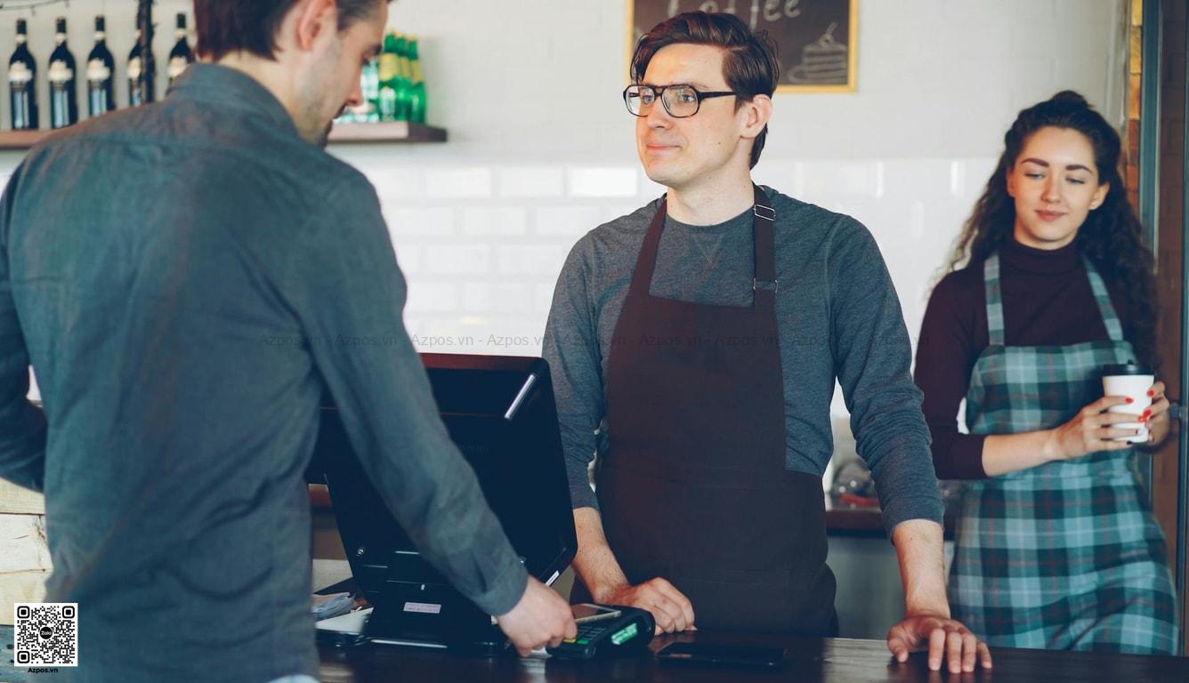 Nhân viên thao tác máy POS tại quầy quán cafe hoặc cửa hàng